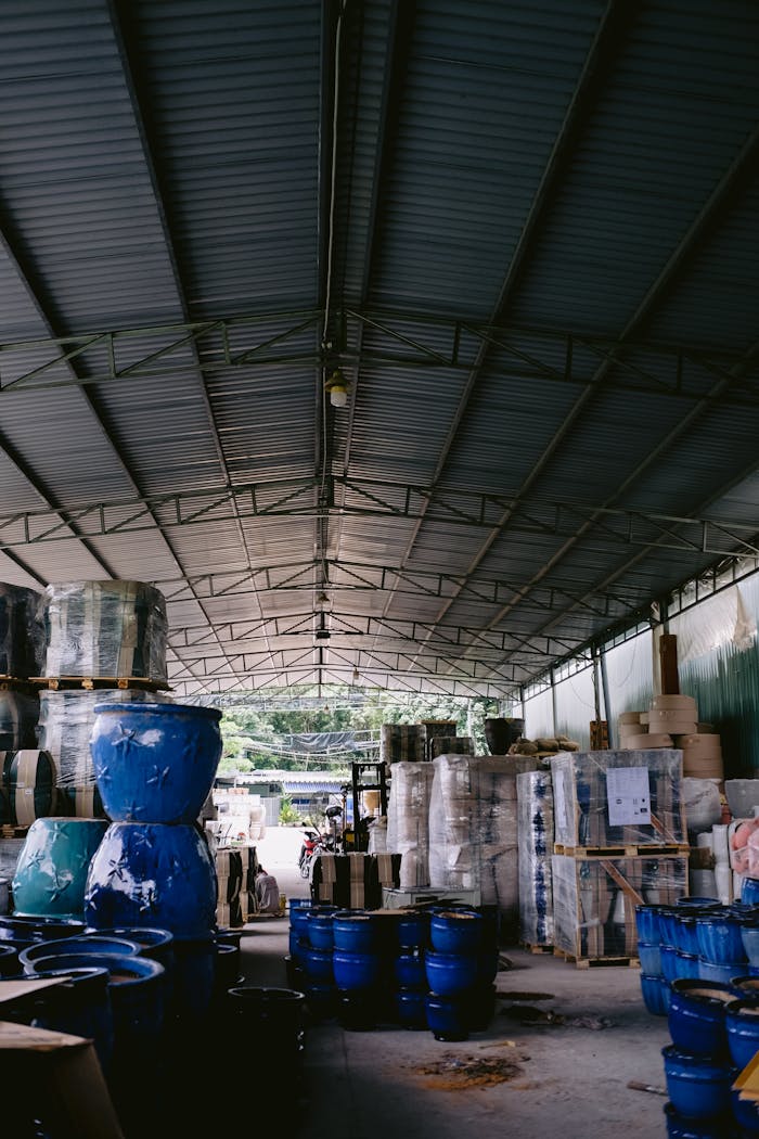 Interior view of a spacious warehouse featuring blue pots and various packed merchandise in a well-organized layout.