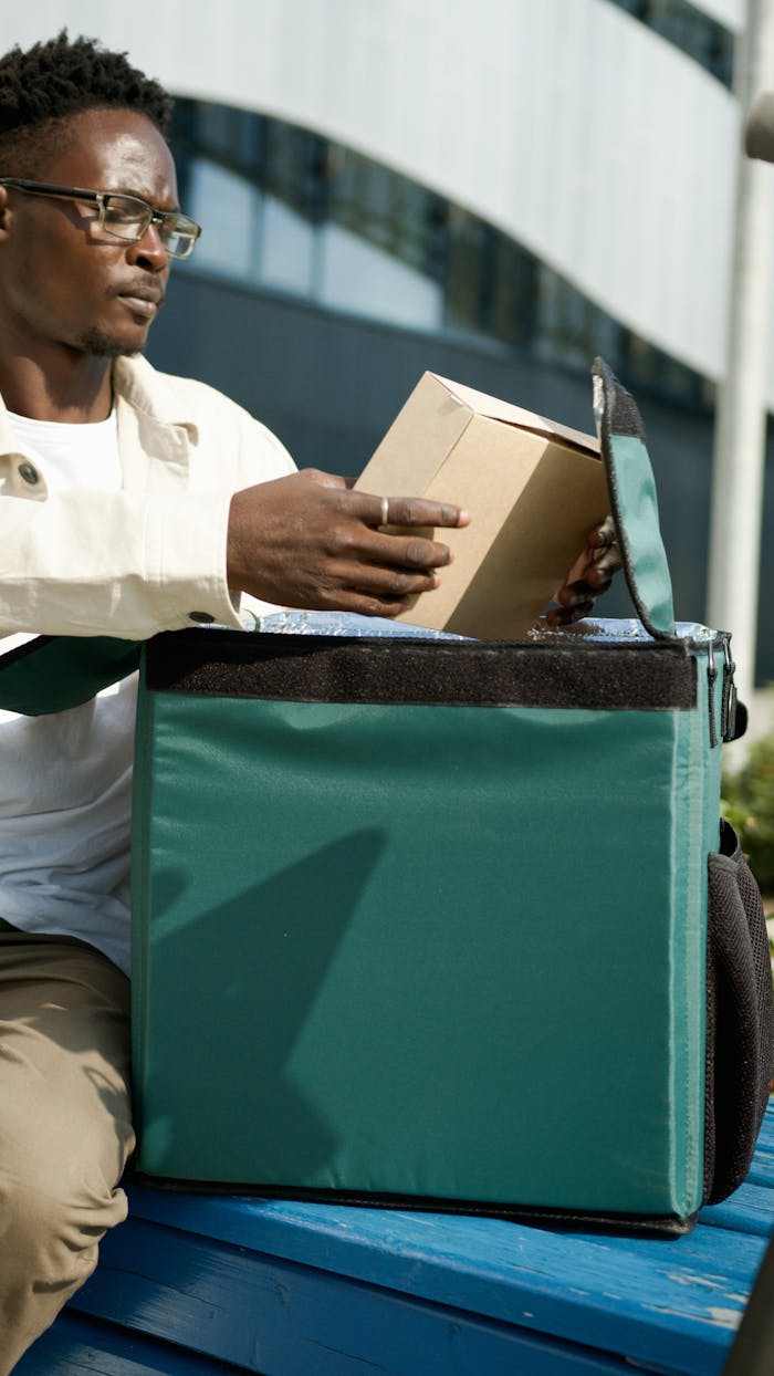 Deliveryman sitting outdoors, handling a package with care, showcasing professional service.